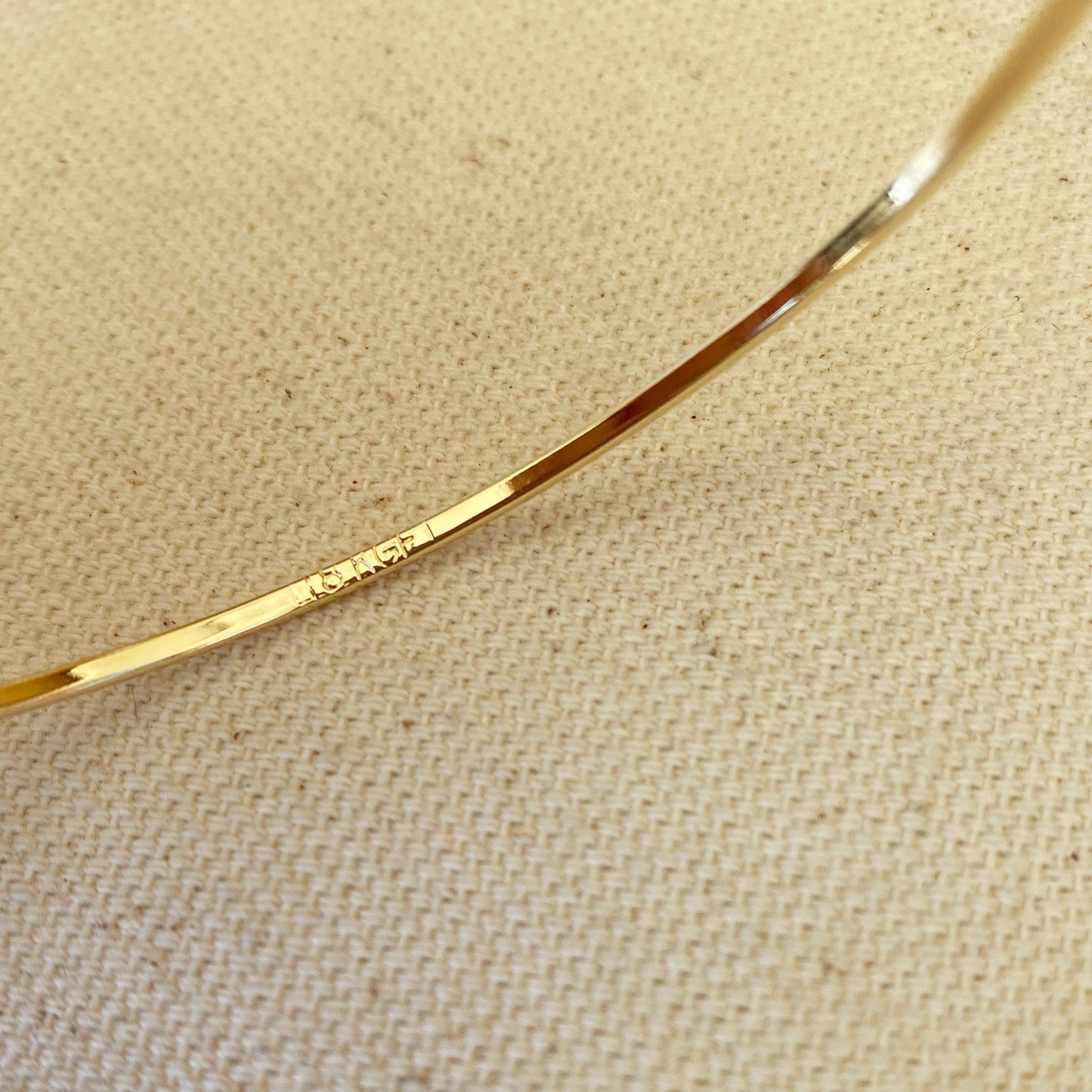 Gold bangle bracelet close up on neutral background