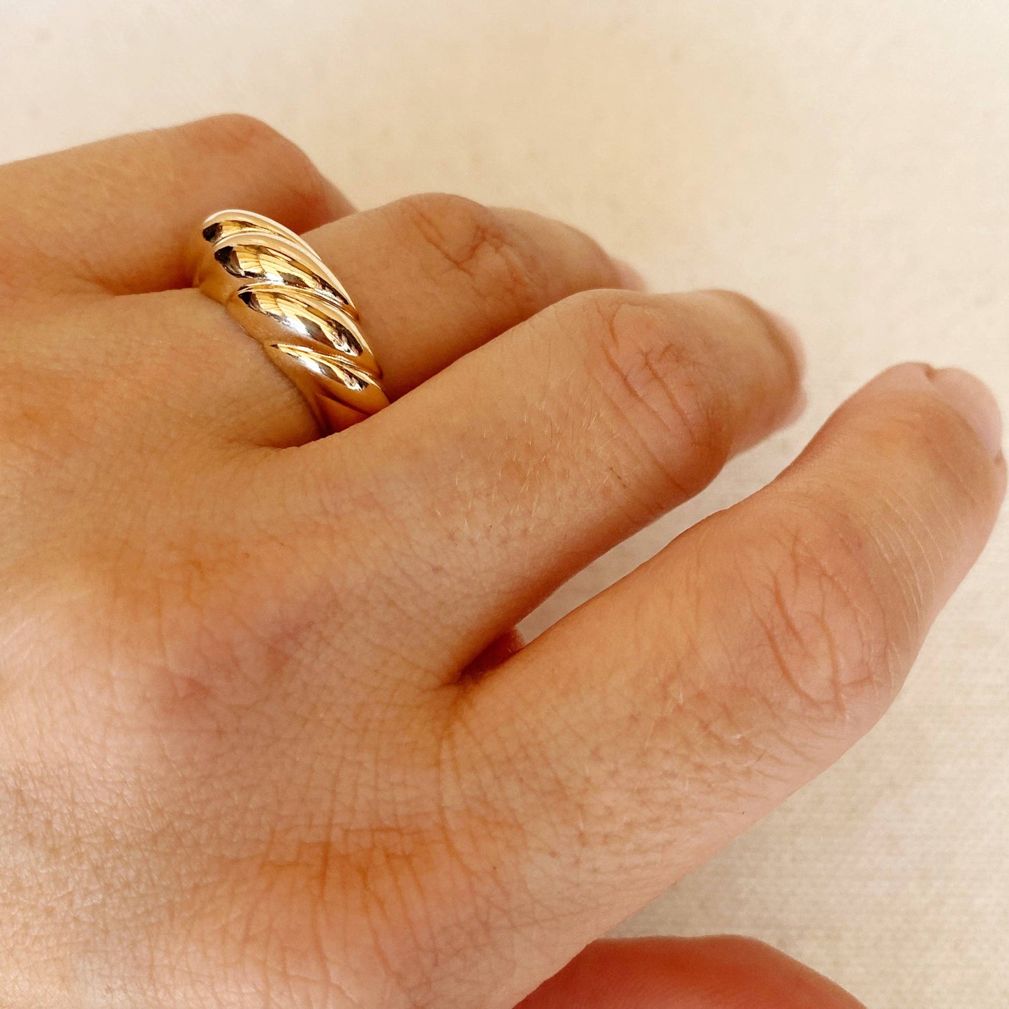 Gold dome croissant shaped ring on woman's finger close up
