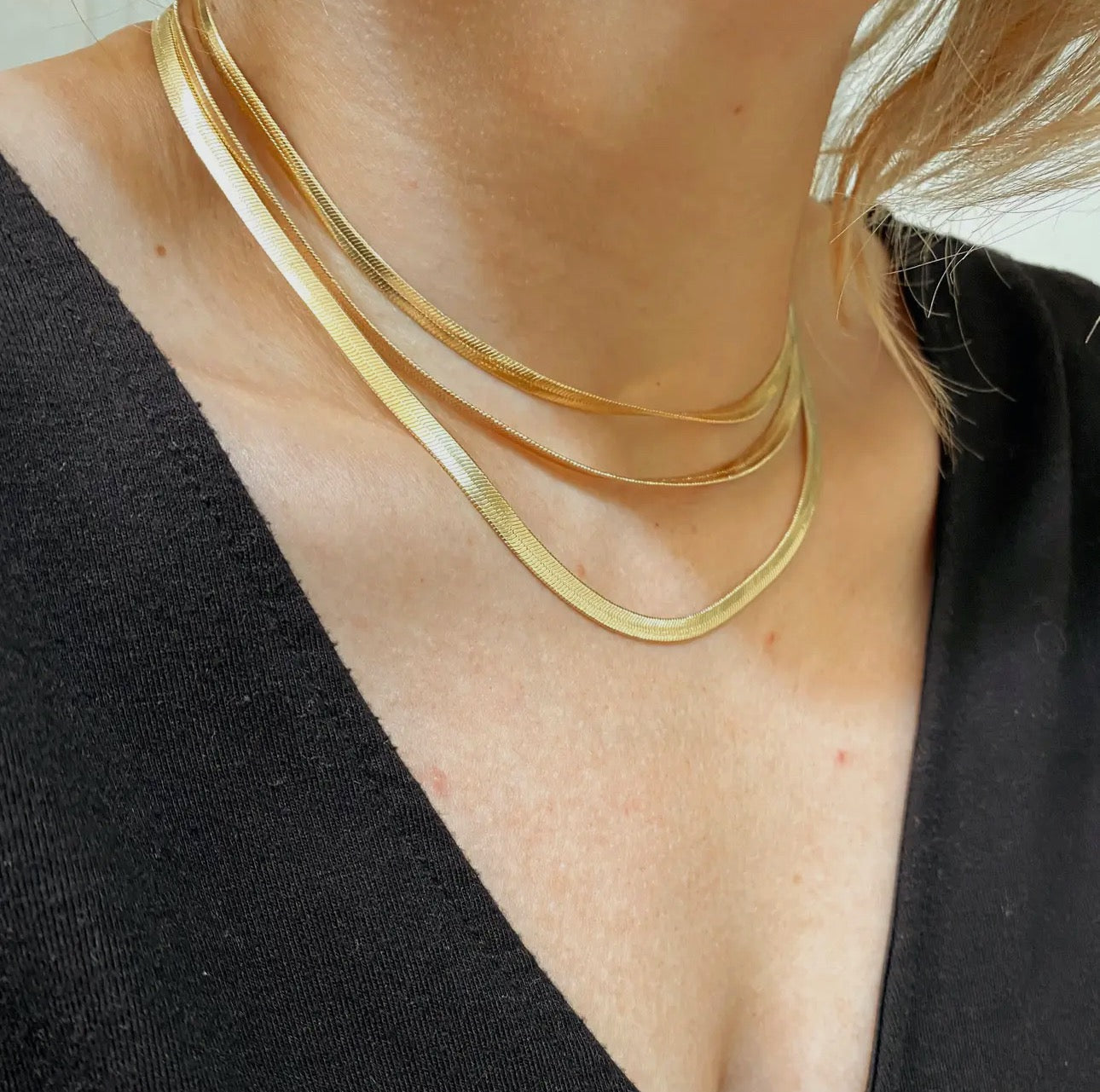14k gold herringbone necklace layered on woman's neck