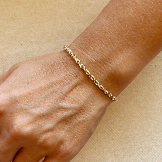 An 18k gold filled braided rope bracelet featuring a lobster clasp, shown close up.
