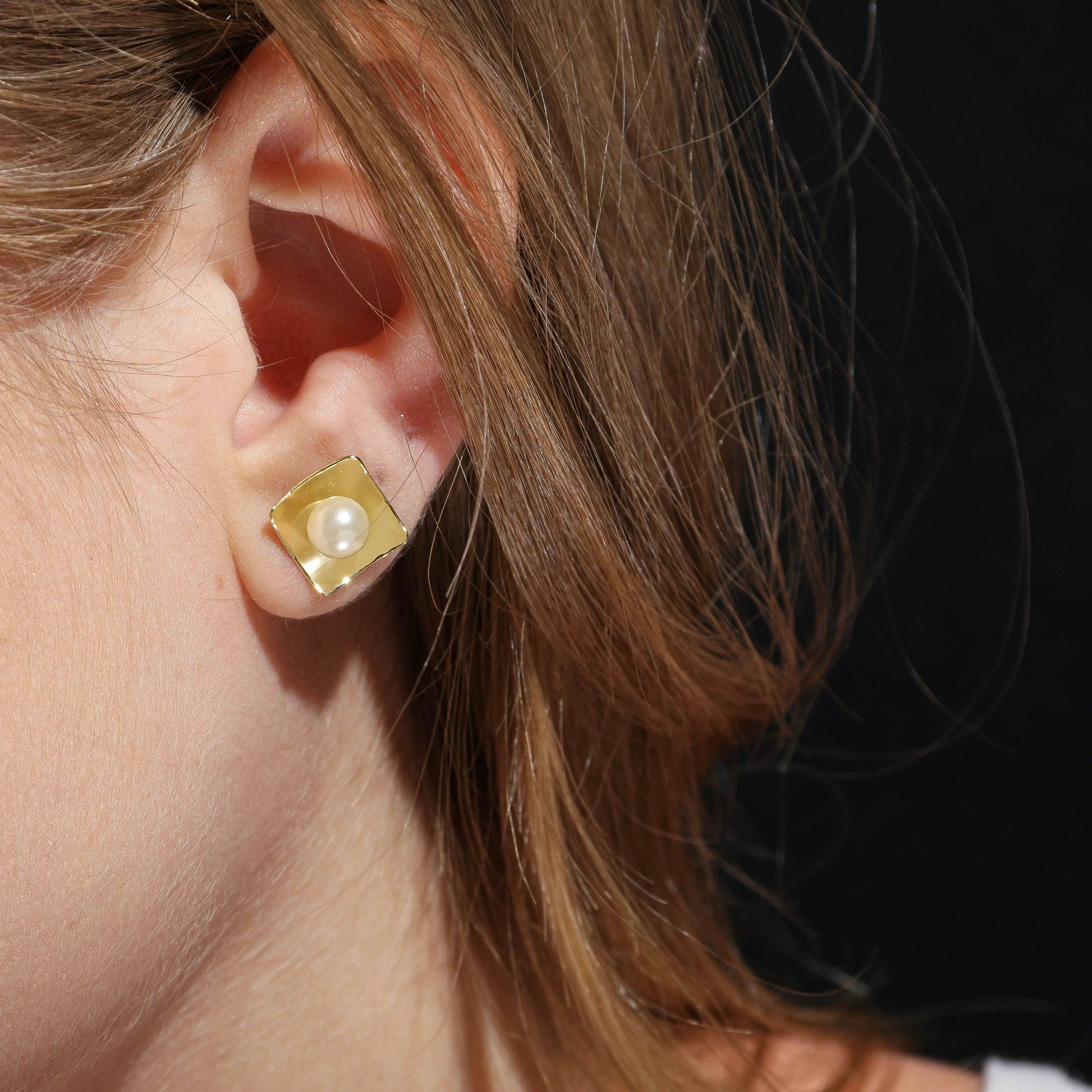 18k gold filled pearl stud earrings showcased on a woman's ear