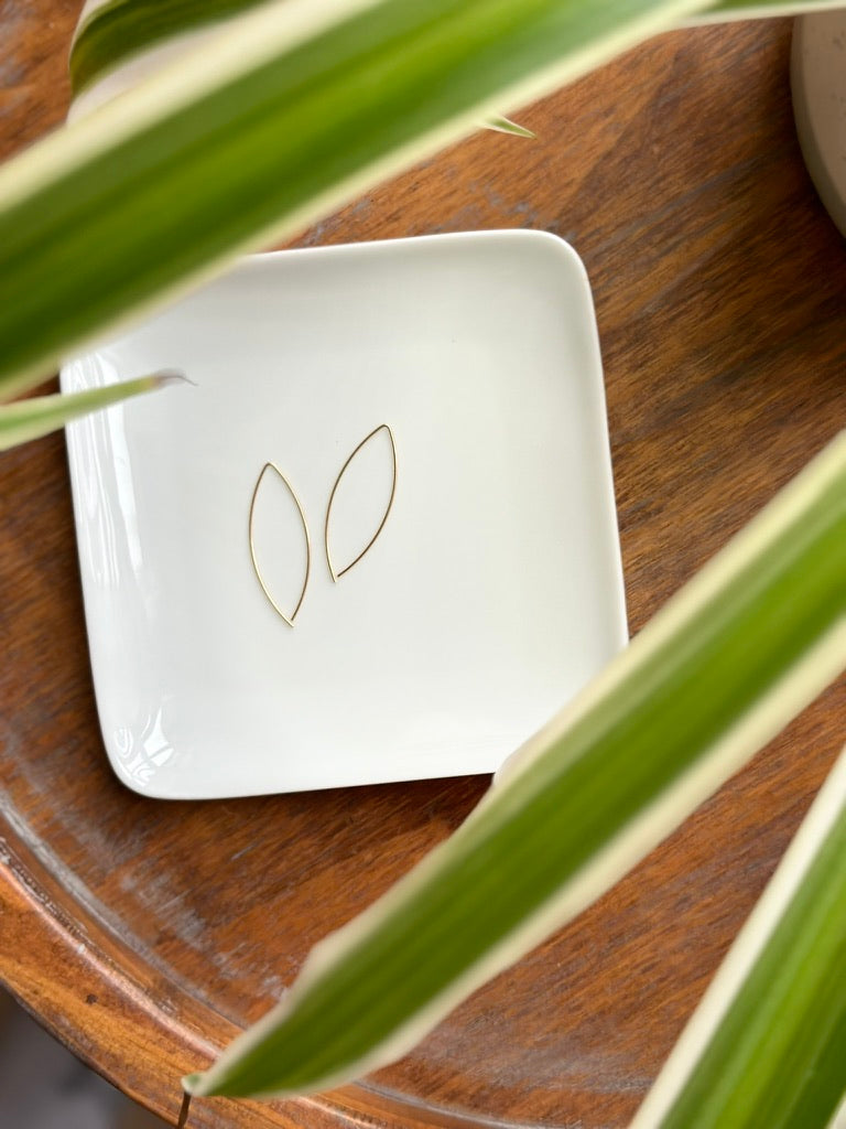 Wire threader earrings that are elegant and minimal, shown on a white dish
