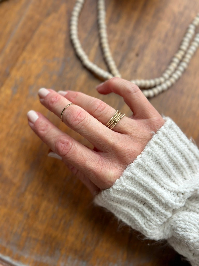 Beaded stacking wire ring in 14k gold fill, shown in stack on woman's hand