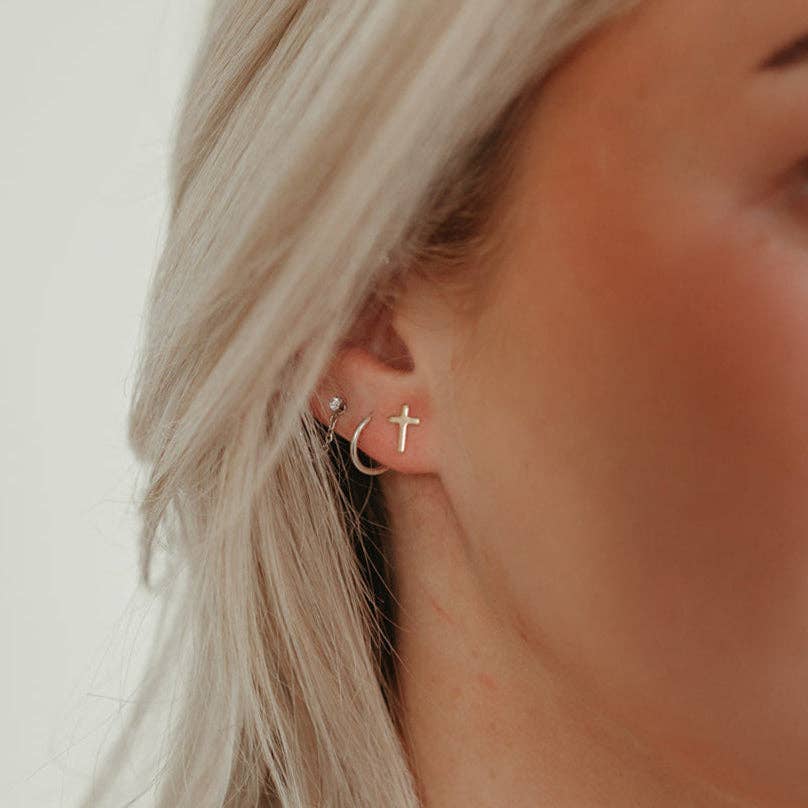 Cross stud earrings in sterling silver worn in woman's ear