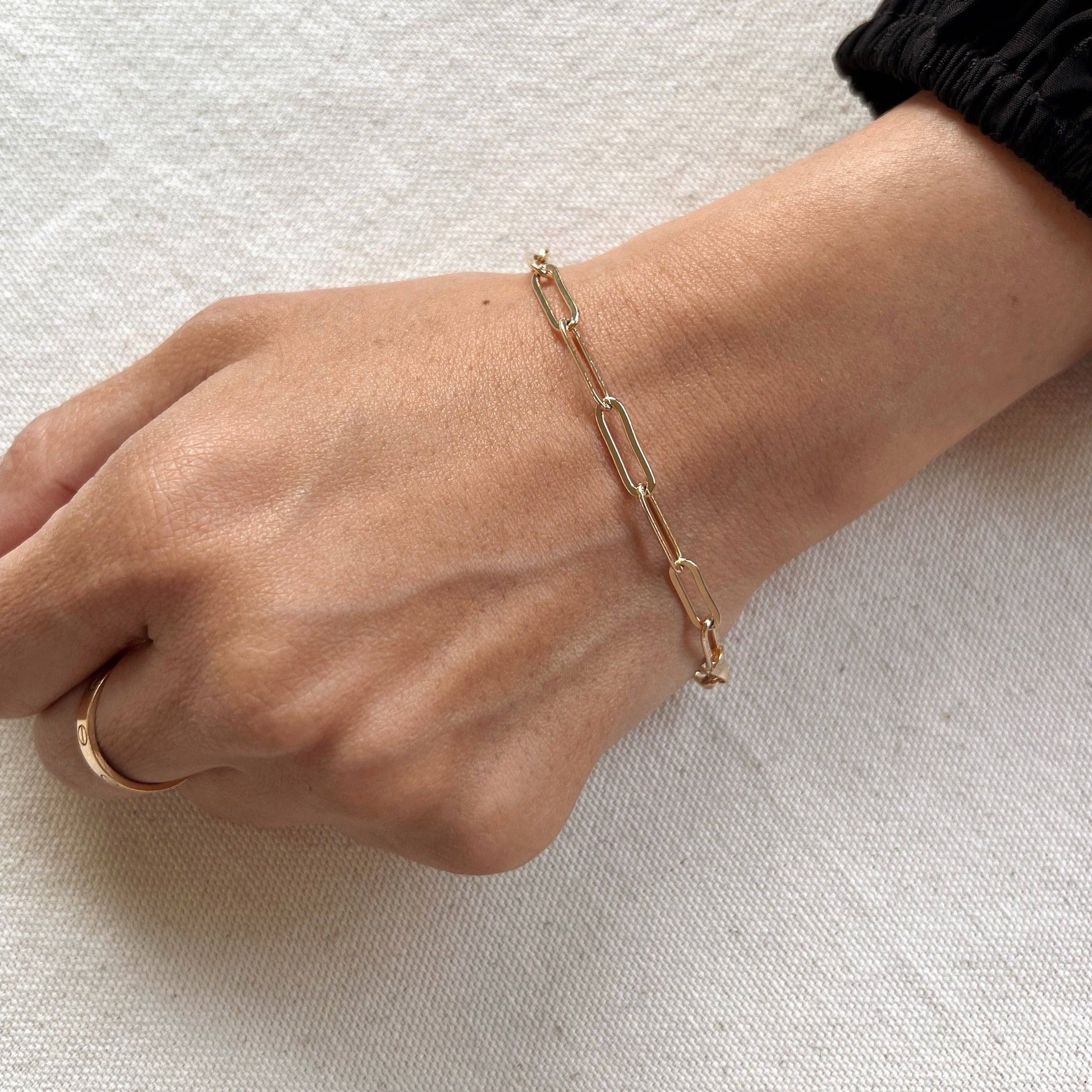 Modern gold paperclip bracelet on woman's wrist.