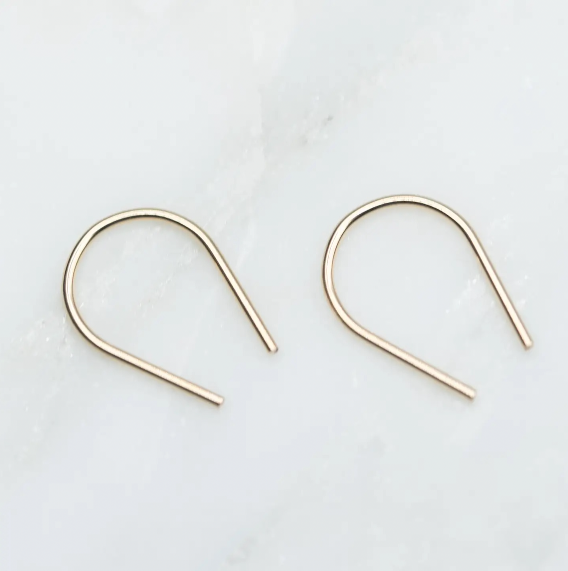 Minimal horseshoe ear wire earrings in gold filled on white background