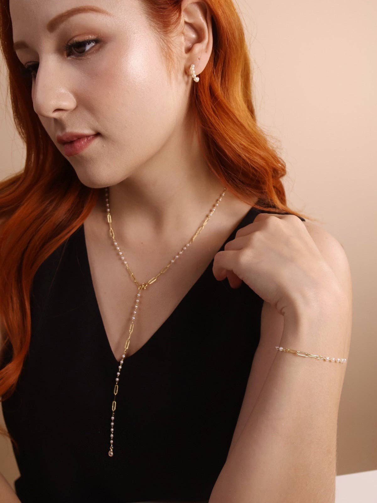 Woman wearing pearl and 18k gold paperclip bracelet on her wrist