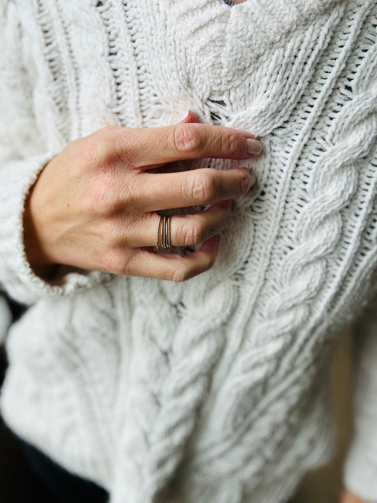 Ring stack in rope style in gold fill on woman's hand with sweater background