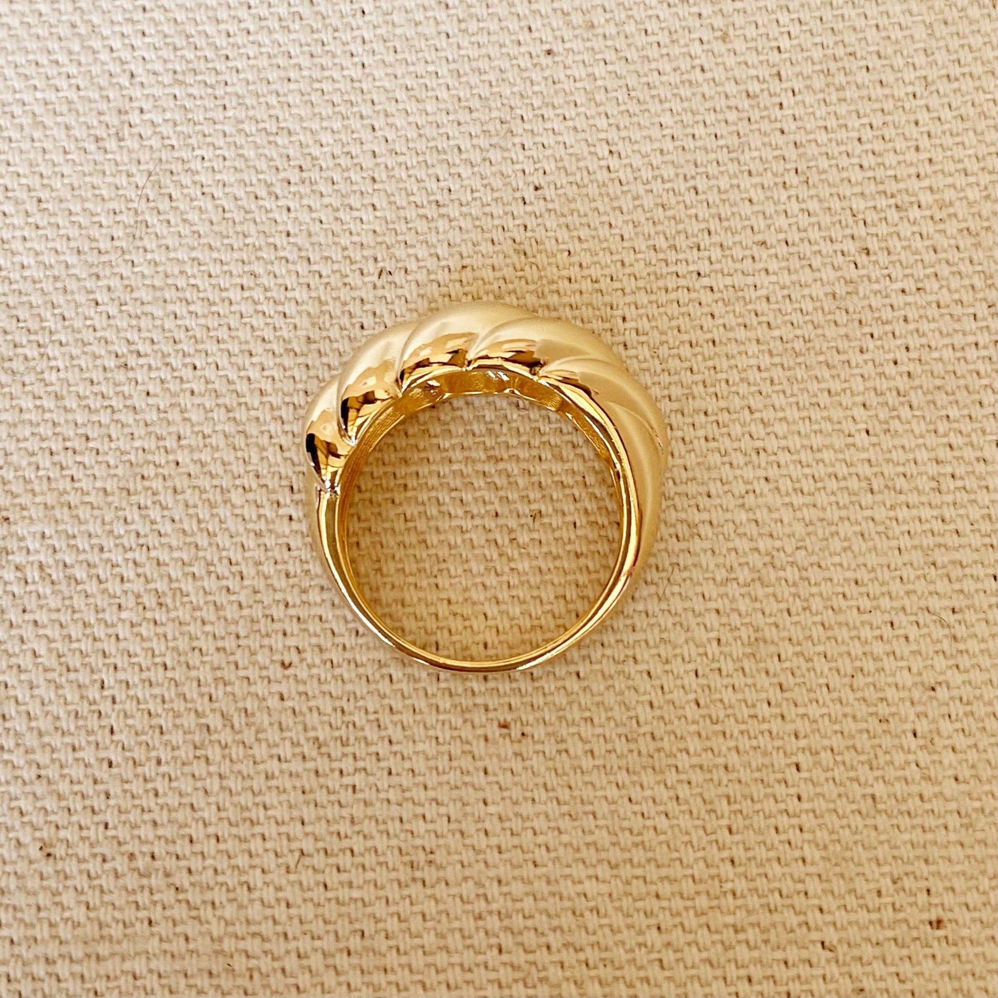 Side view of dome croissant shaped ring in gold on textured background