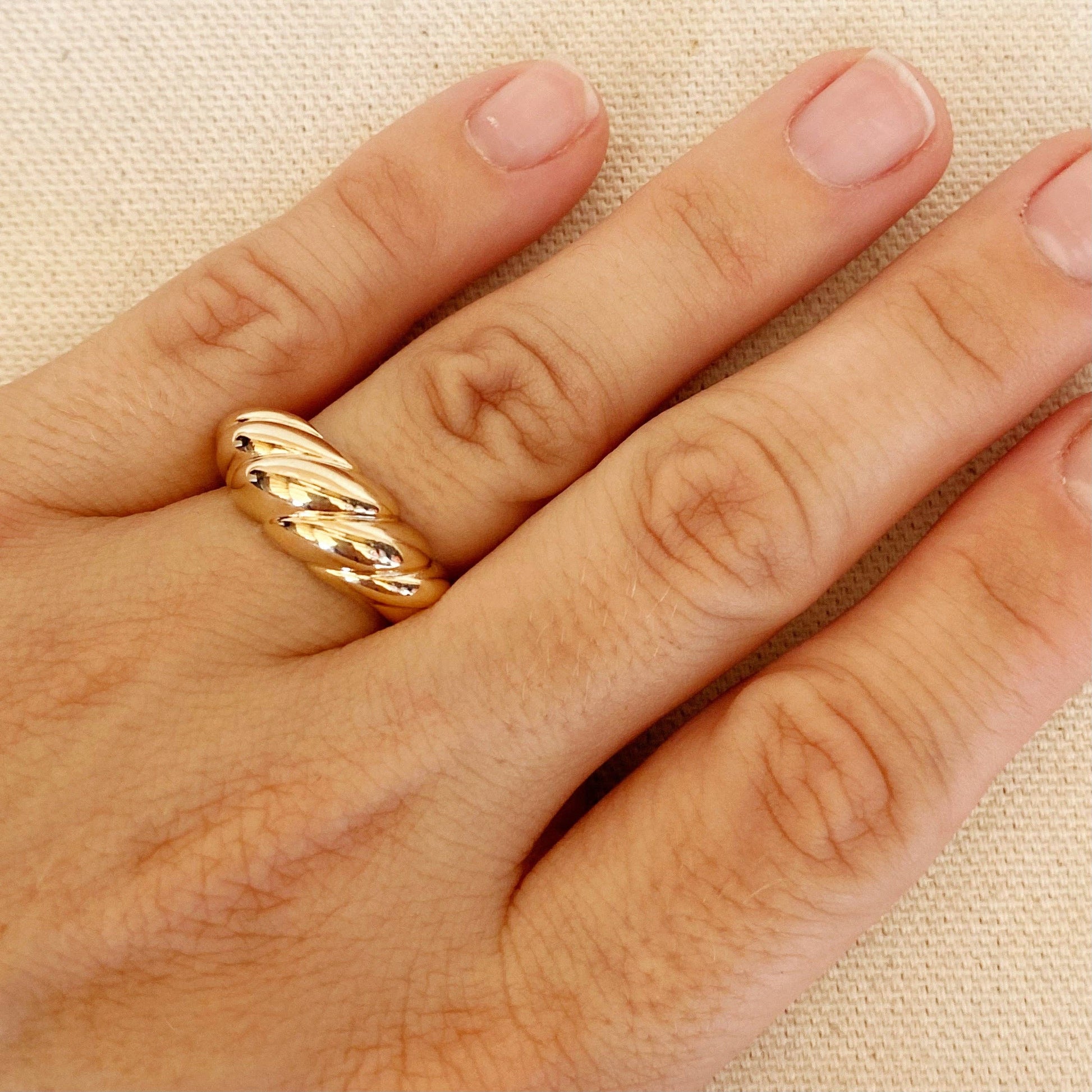 Woman's hand wearing dome croissant shaped ring in gold 
